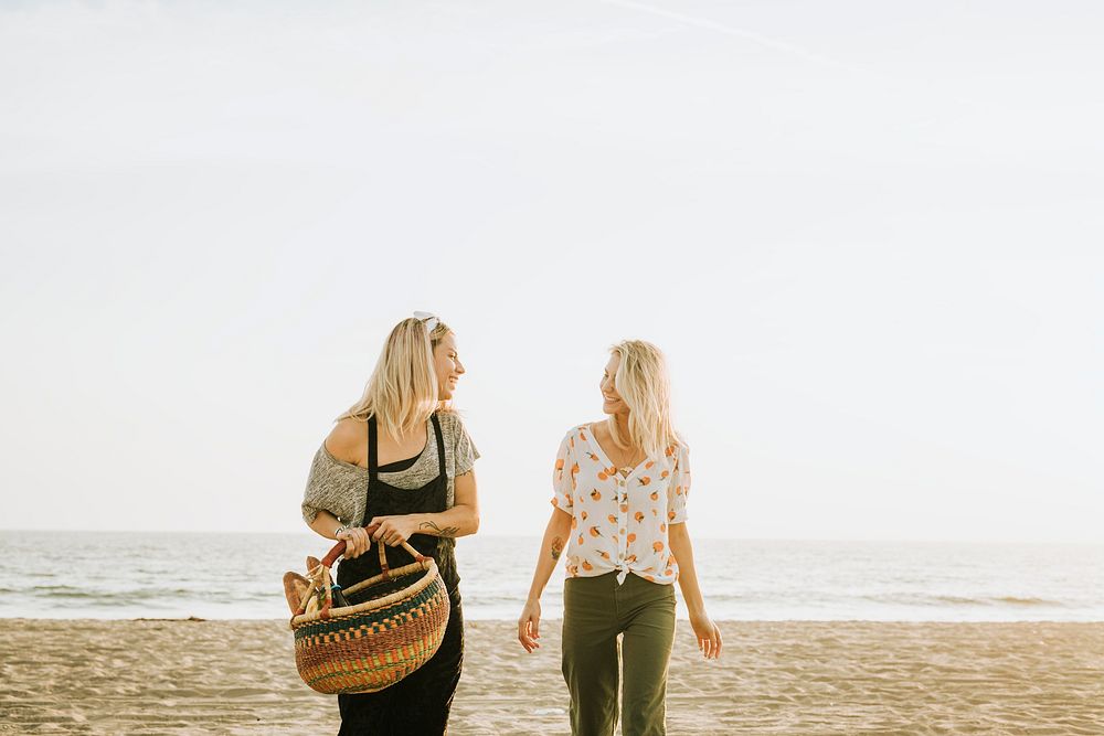 Friends walking at the beach with a picnic basket