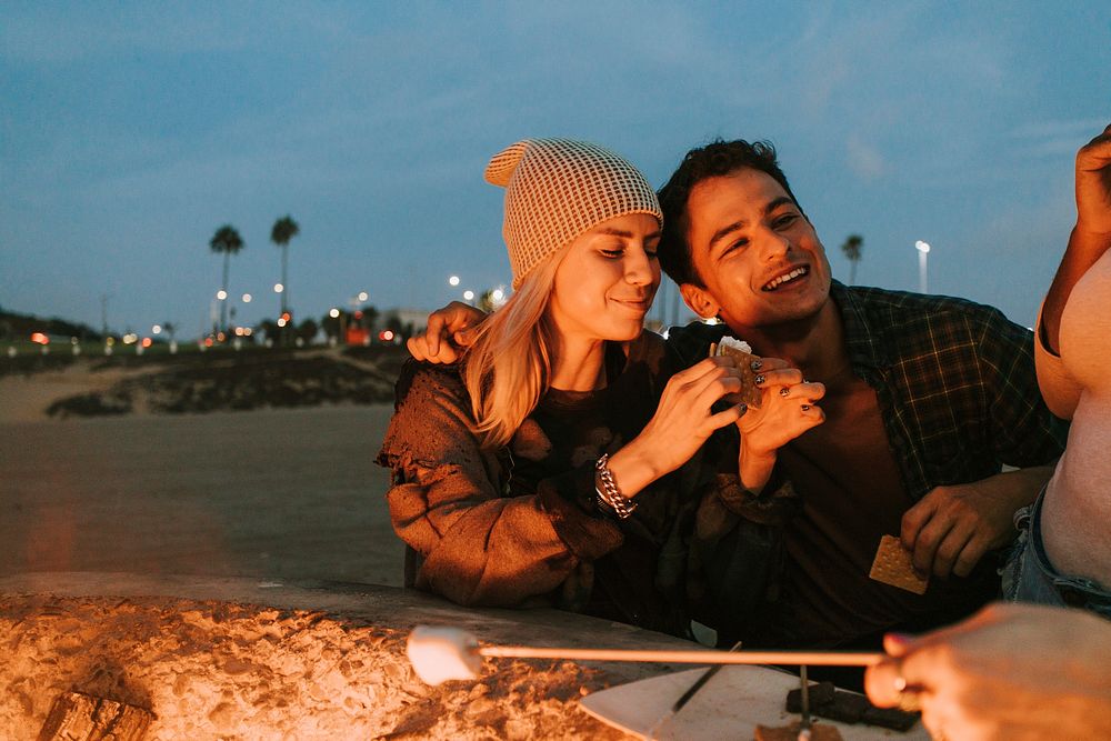 Couple having a s'more at the beach