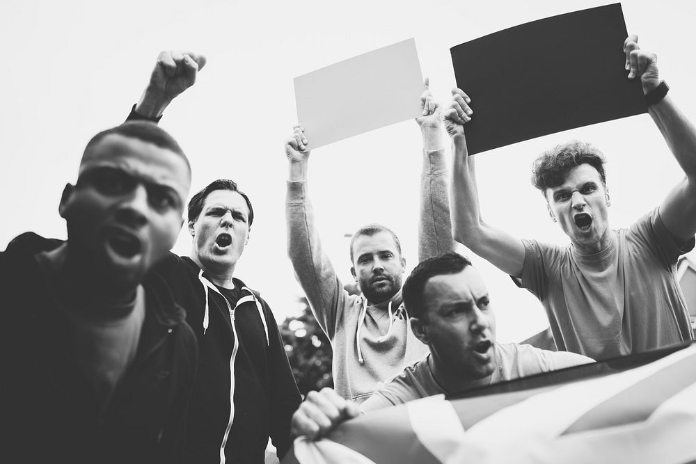 Group of angry men showing a UK flag and blank boards shouting during a protest