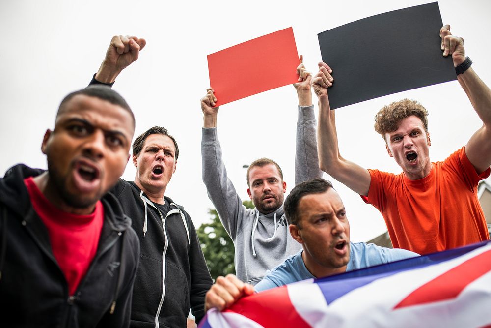 Group of angry men showing a UK flag and blank boards shouting during a protest
