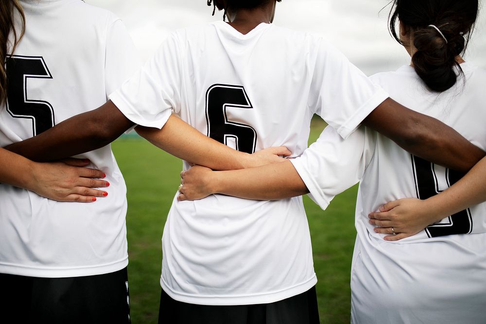 Female soccer players huddling and standing together