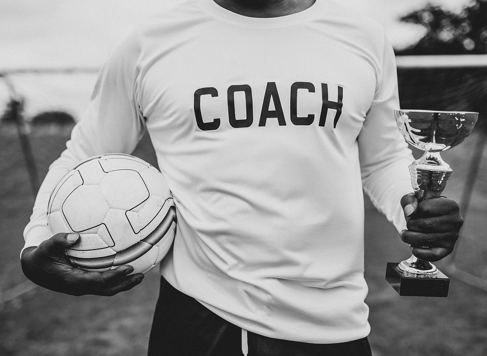 Soccer coach holding a trophy cup and ball
