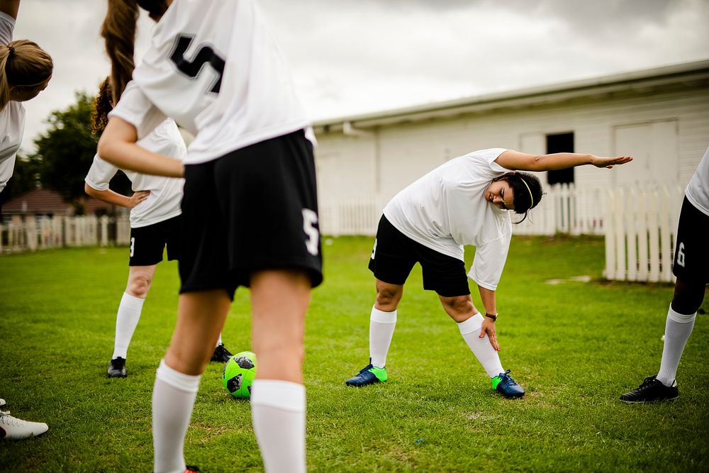 Female soccer team players stretching pre game