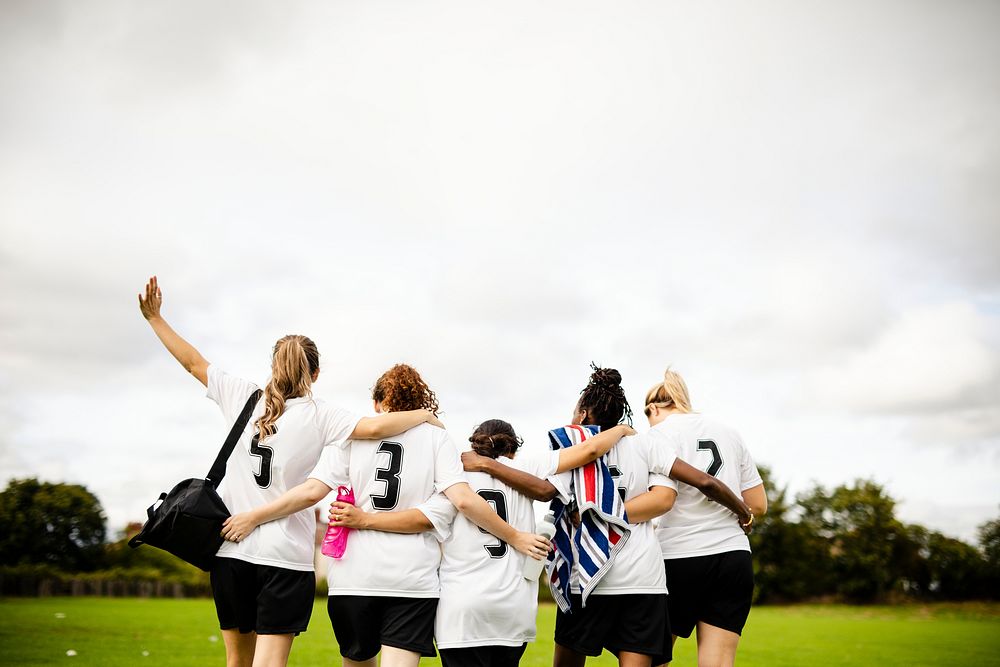 Female football players huddling and walking together