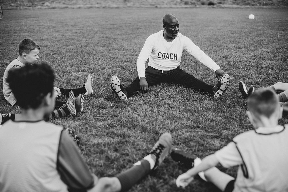 Football coach stretching with junior players