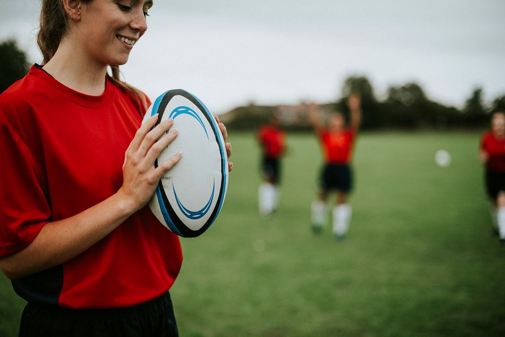 Happy female rugby player holding a ball