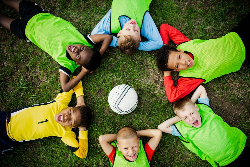 Junior football team lying around a football