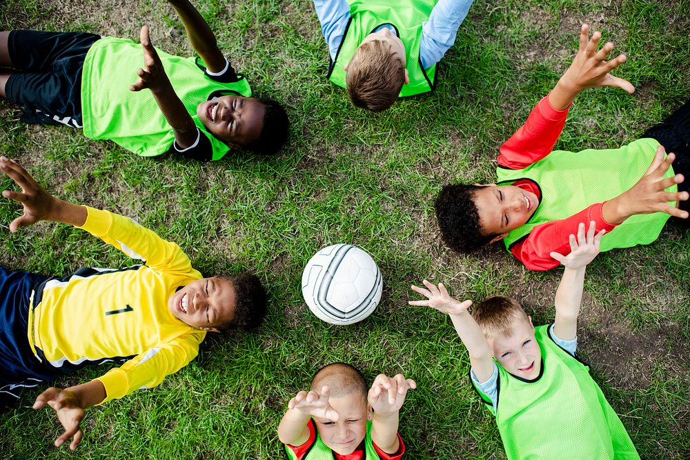 Junior football team lying around a football