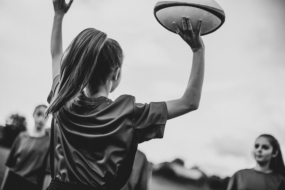 Female rugby player jumping with a ball