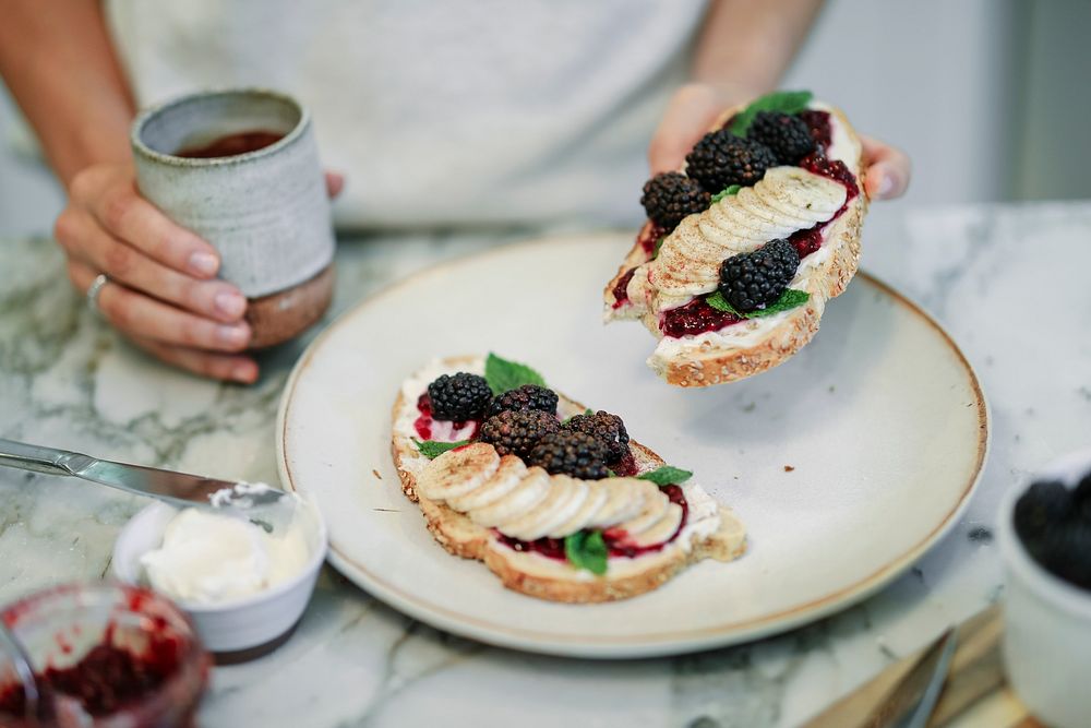 Woman having a toast with blackberry jam and vegan cream cheese