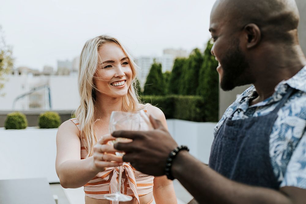 Happy couple toasting with a glass of wine at a rooftop party