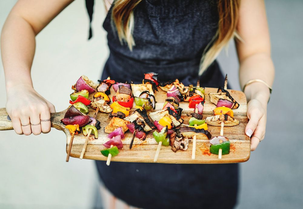 Woman serving vegan barbecue skewers on a wooden board