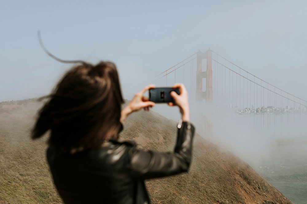 Woman taking a photograph of the Golden Gate Bridge, San Francisco
