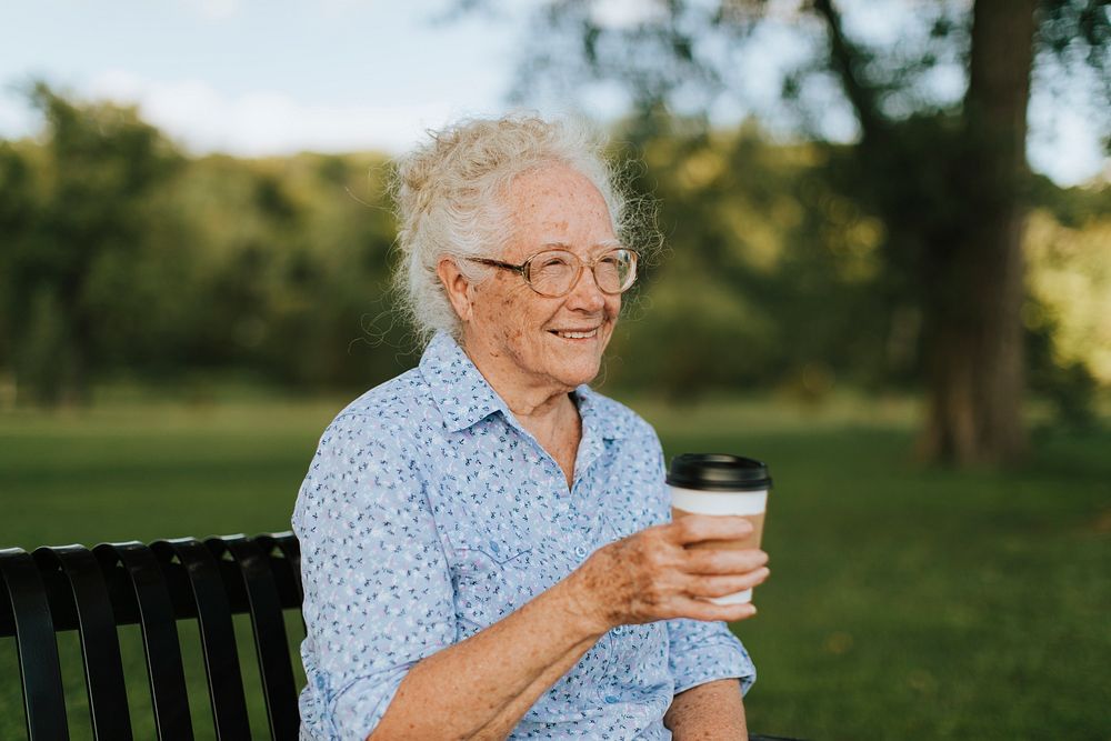 Happy senior woman having a takeaway coffee at the park