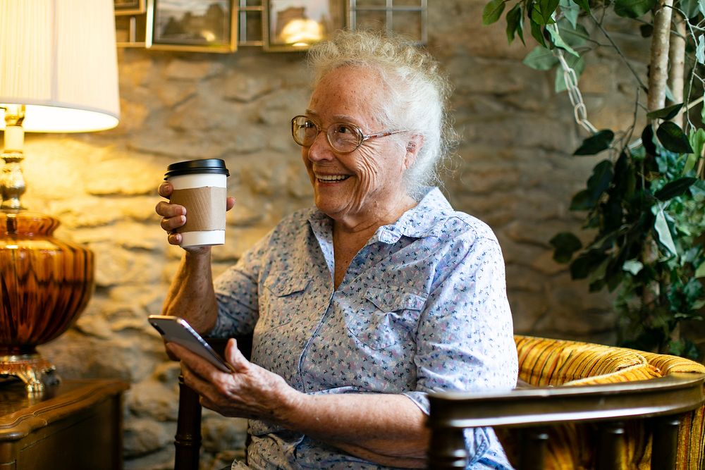 Elderly woman drinking coffee and using her phone