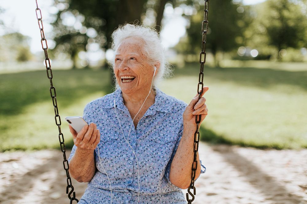 Cheerful senior woman listening to music at a playground