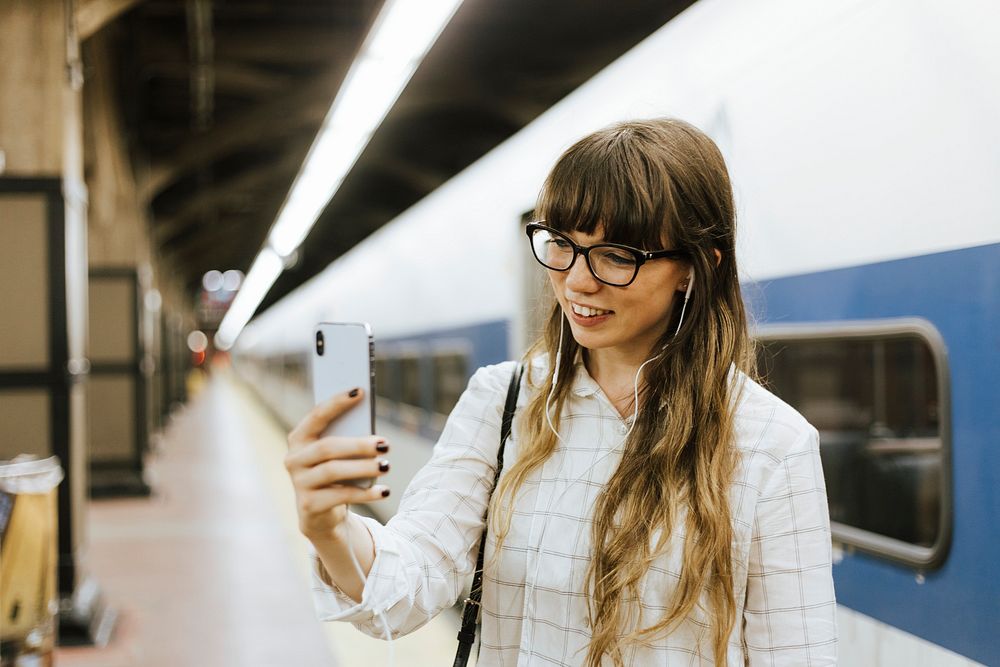 Cheerful woman having a video call at a subway platform