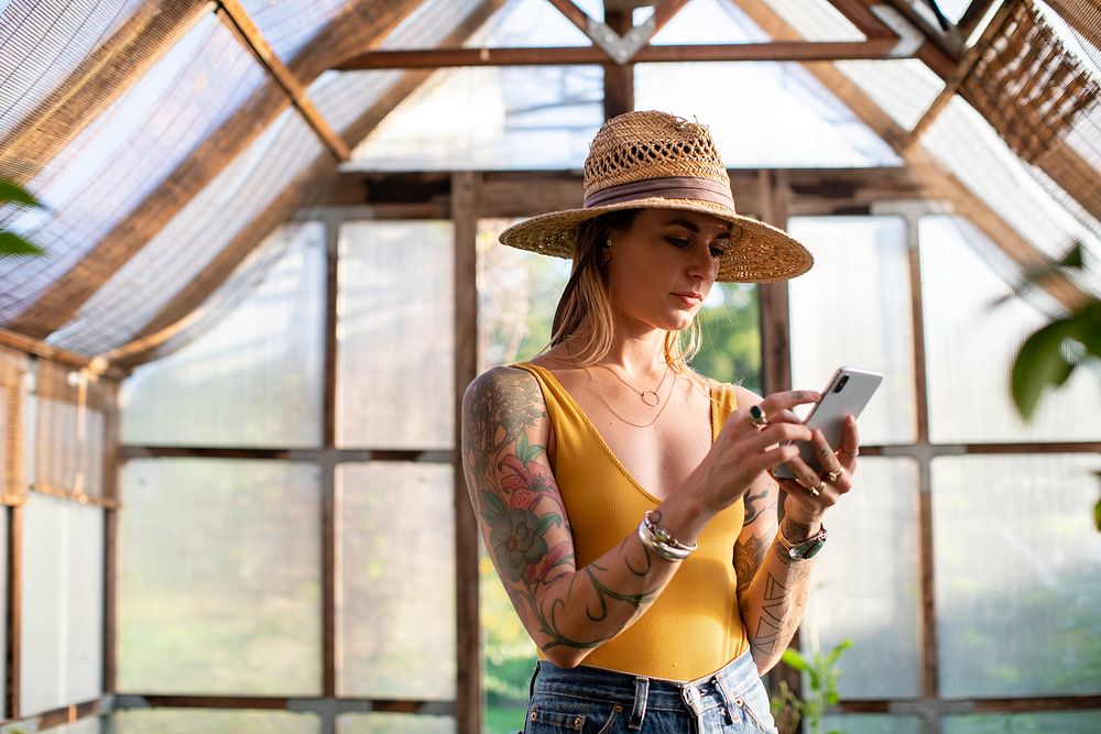 Gardener using her phone in the greenhouse