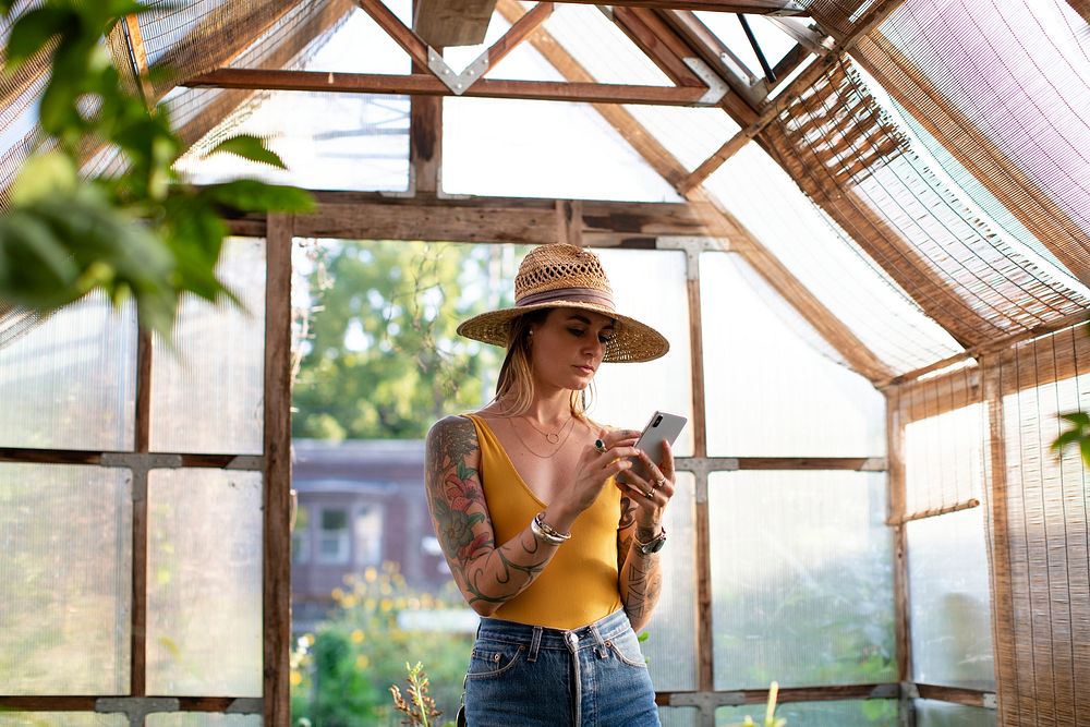 Gardener using her phone in the greenhouse