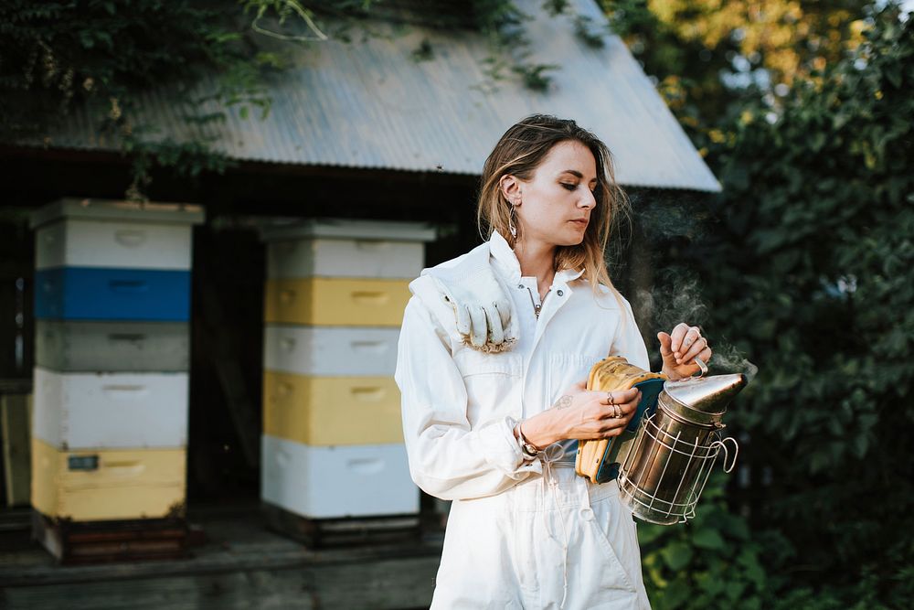 Beekeeper with the smoker and her bee hives