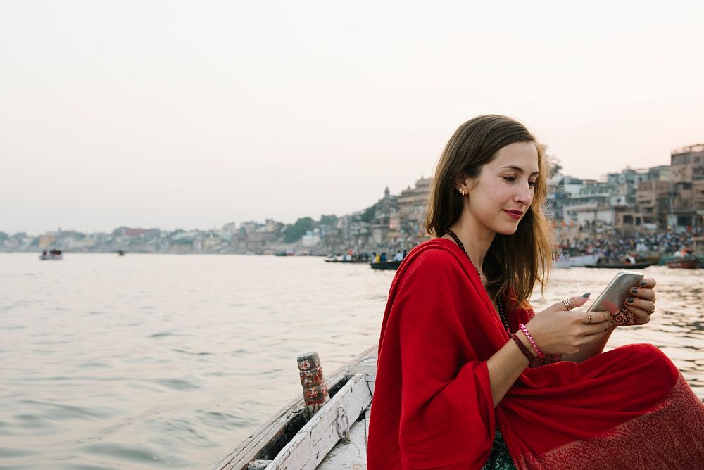 Western woman on a boat texting from the River Ganges