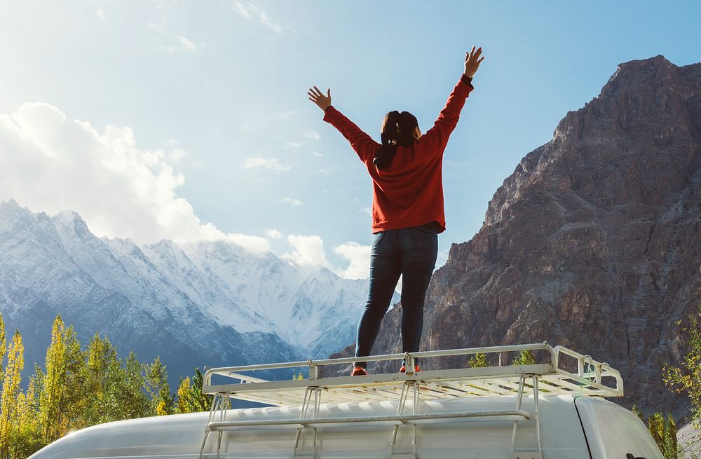 Woman standing on a van facing the beautiful mountain