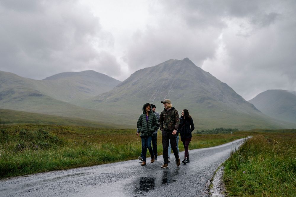 Friends walking down a wet road in Glen Etive, Scotland