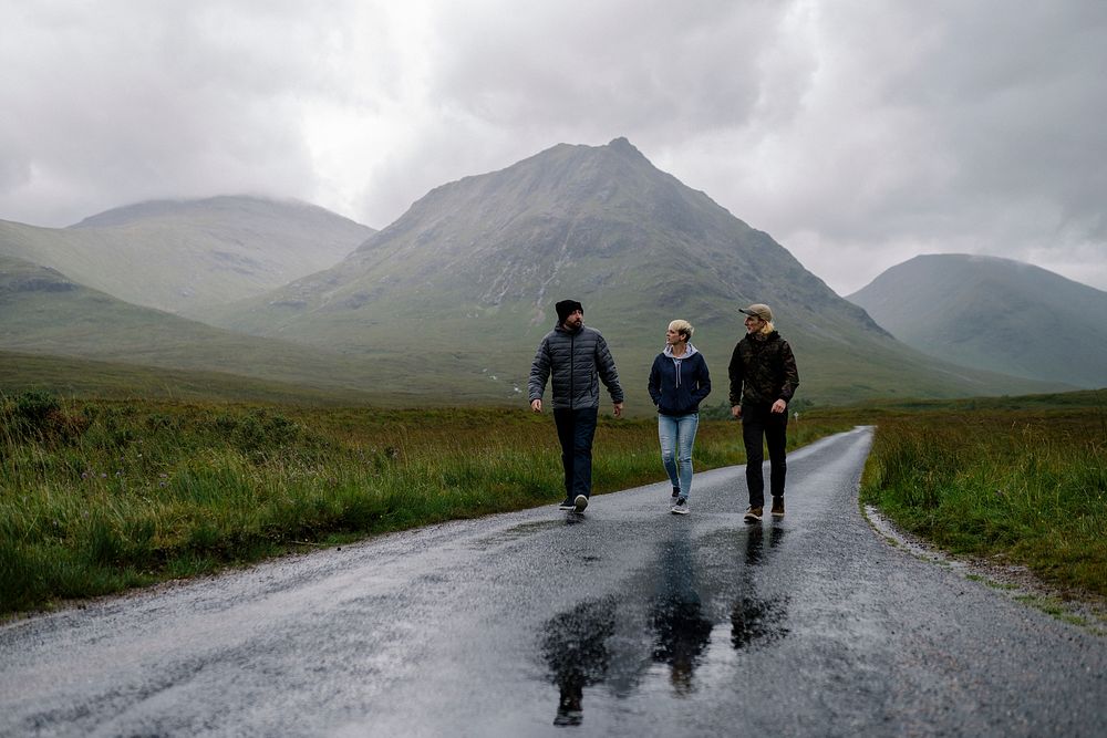 Friends walking down a wet road in Glen Etive, Scotland