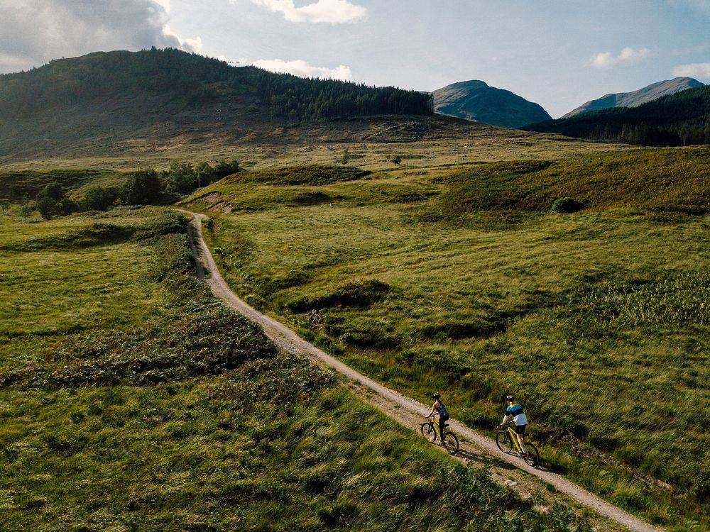 Couple cycling down a road in the Scottish Highlands