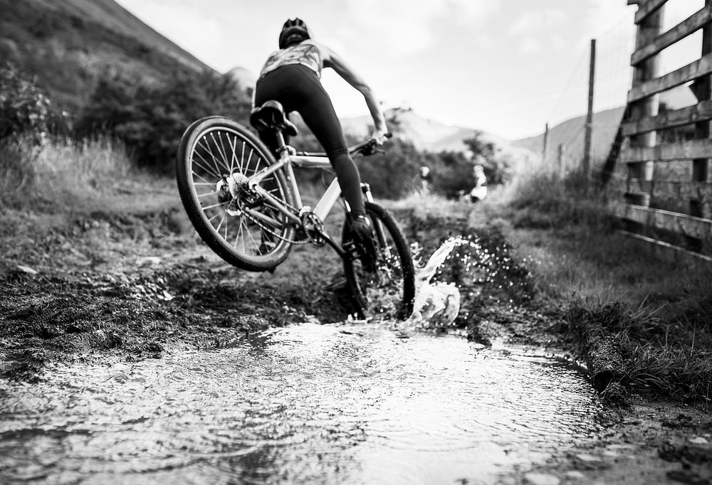 Female cyclist in action over a puddle