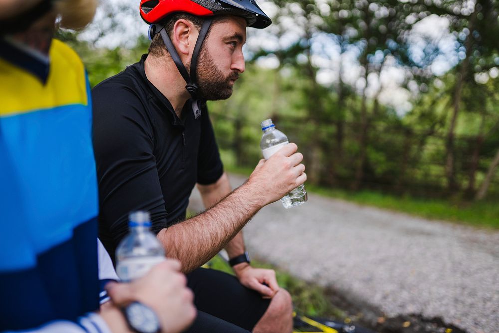 Cyclist resting and drinking water in the forest