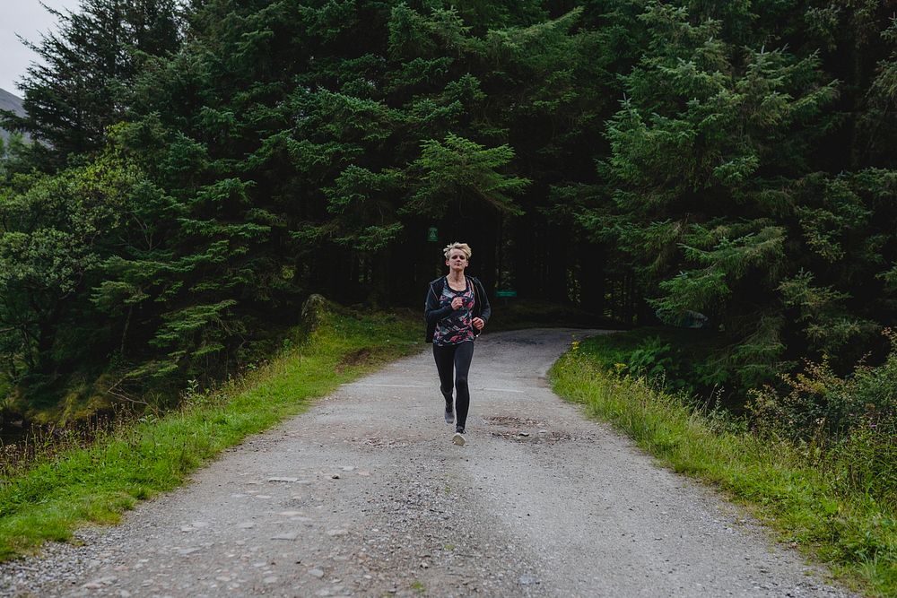 Woman jogging down an empty forest road