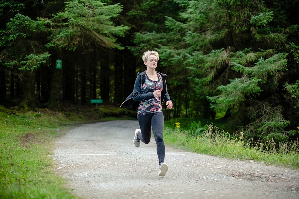 Woman running on a road through the forest