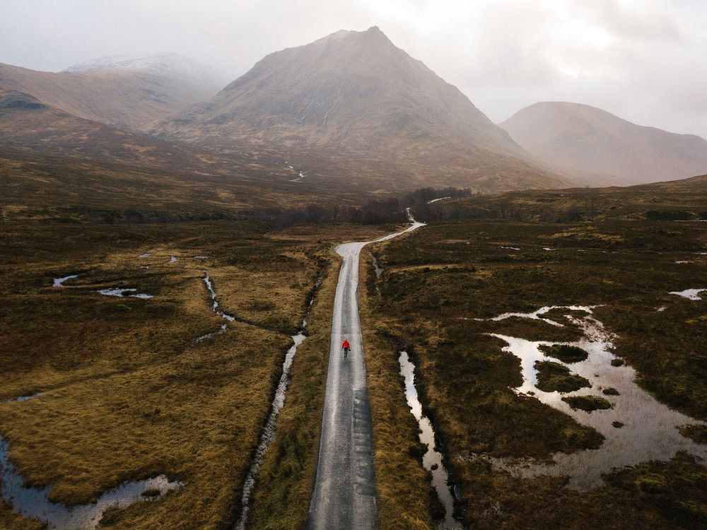 Woman walking on a road in Glen Etive, Scotland