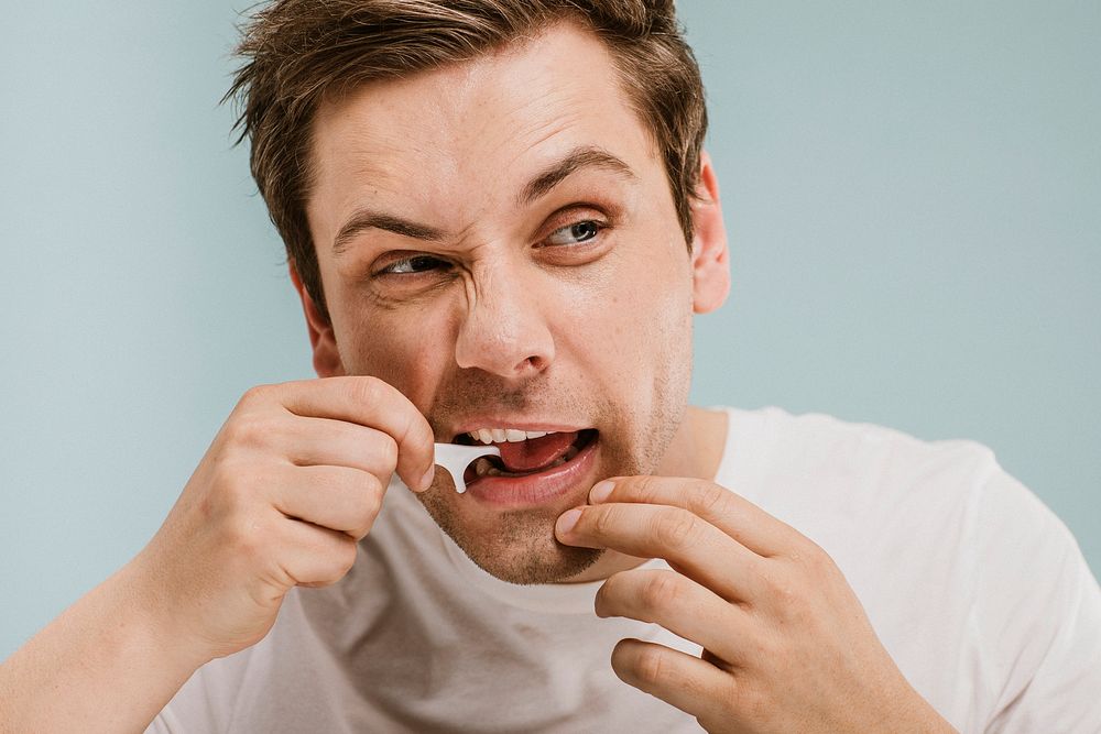 Man using a dental floss pick