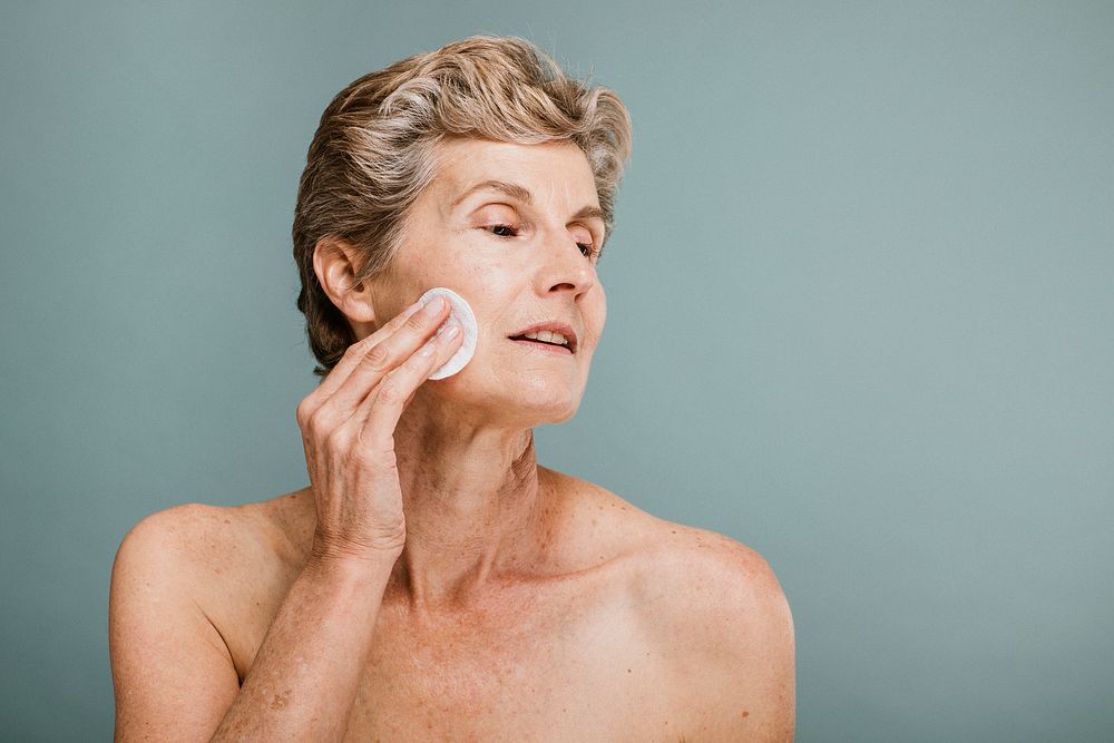Elderly woman wiping her face with a cotton pad