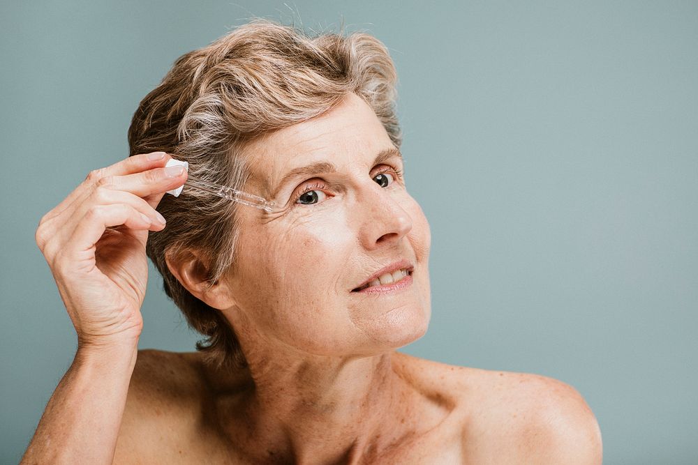 Senior woman applying moisturizer on her eye wrinkles