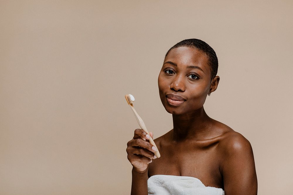 Black woman holding a wooden toothbrush