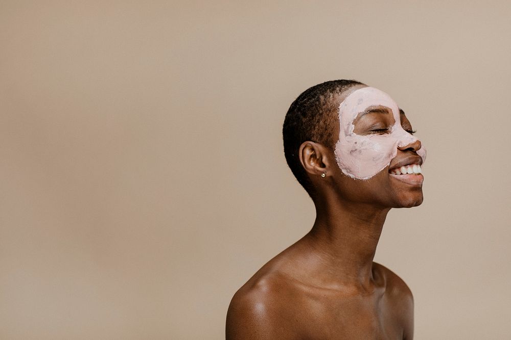 Happy black woman doing a face mask