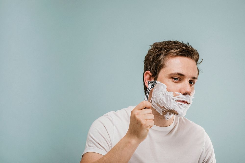 Young man shaving his beard