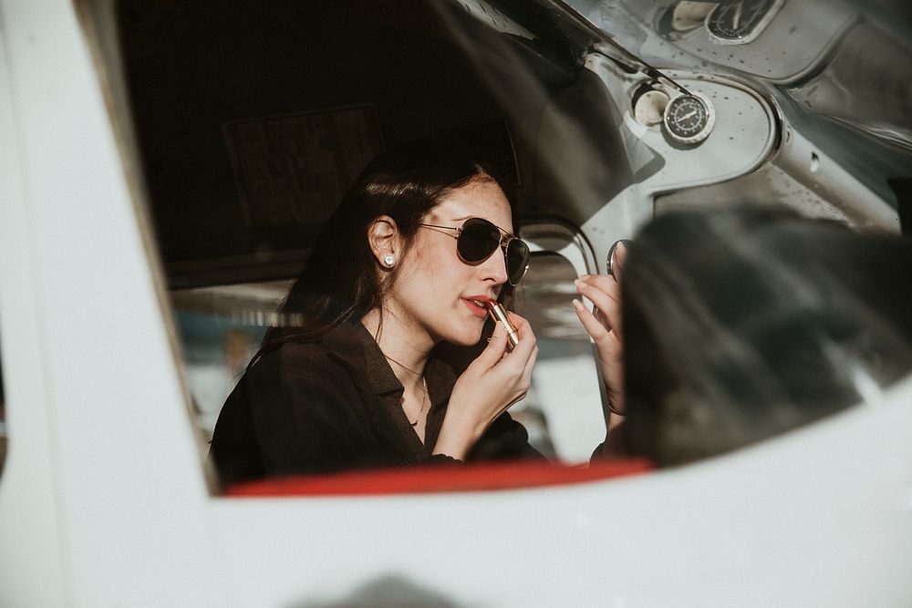 Airwoman applying red lipstick in the cockpit