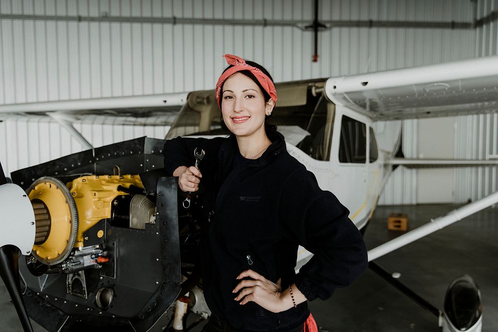 Female aviation technician repairing the motor of a propeller plane