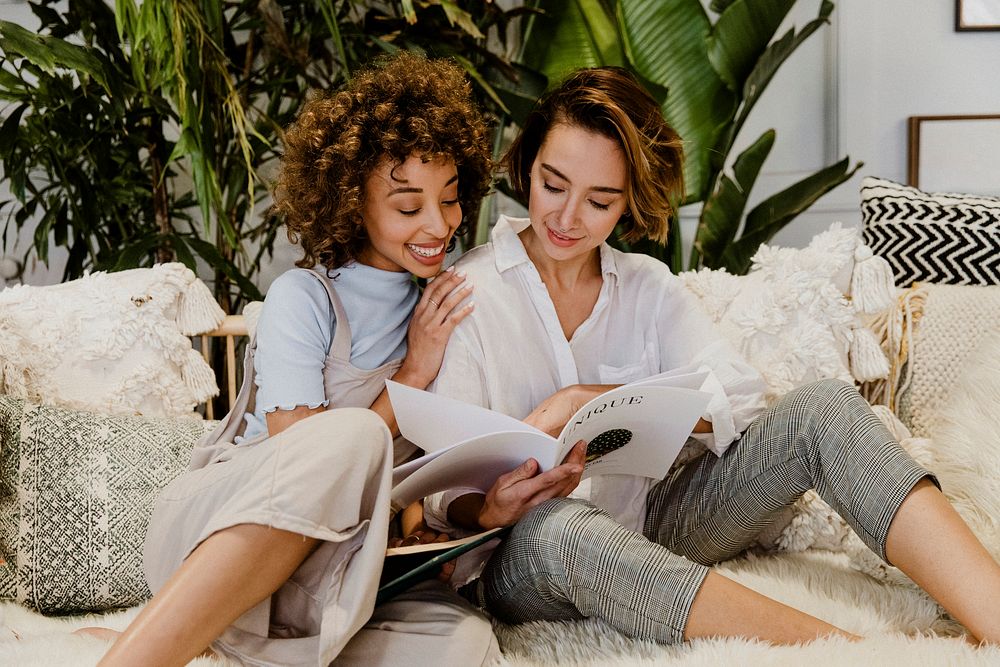 Cheerful lesbian couple reading books on a couch