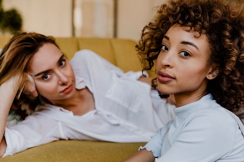 Portrait of a cheerful lesbian couple at a yellow couch