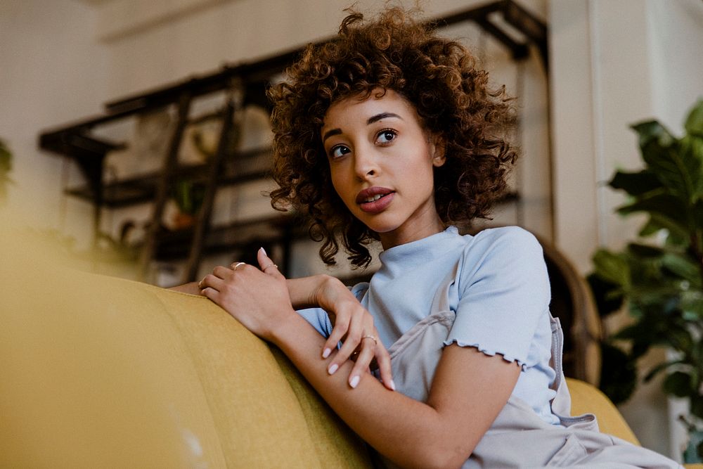 Woman sitting on a mustard yellow couch