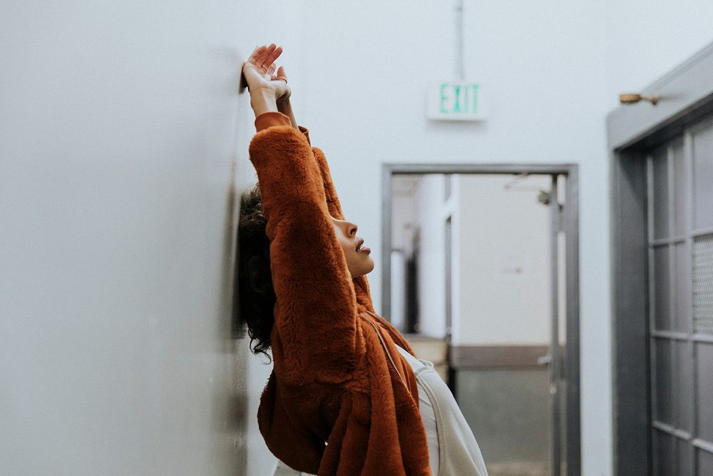 Woman in a brown coat leaning against a wall