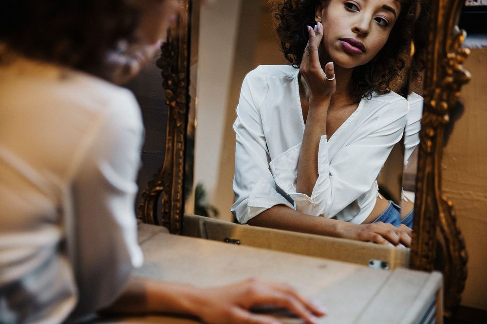 Woman looking in a mirror desolately