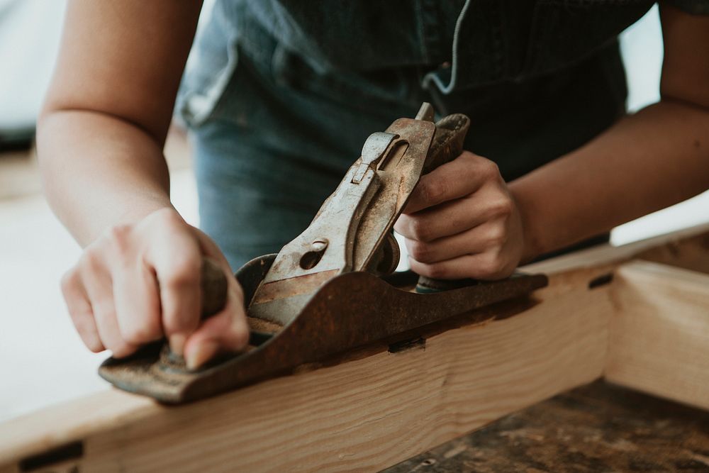 Female carpenter shaping lumber with a hand plane