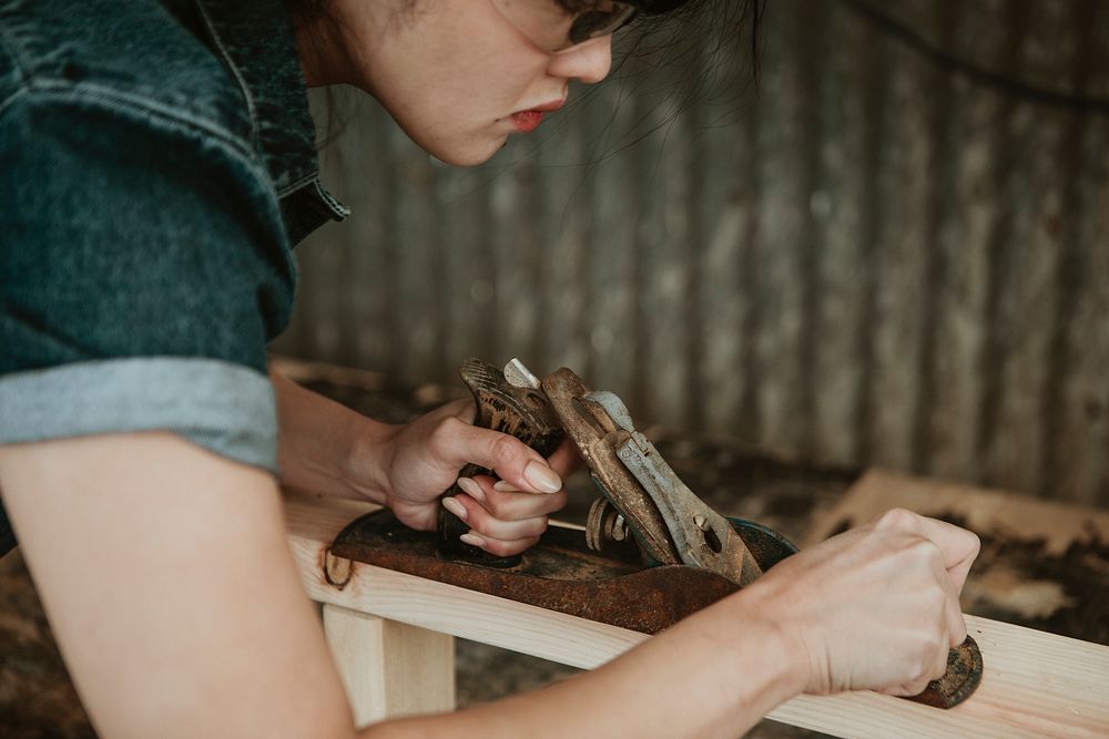 Female carpenter shaping lumber with a hand plane