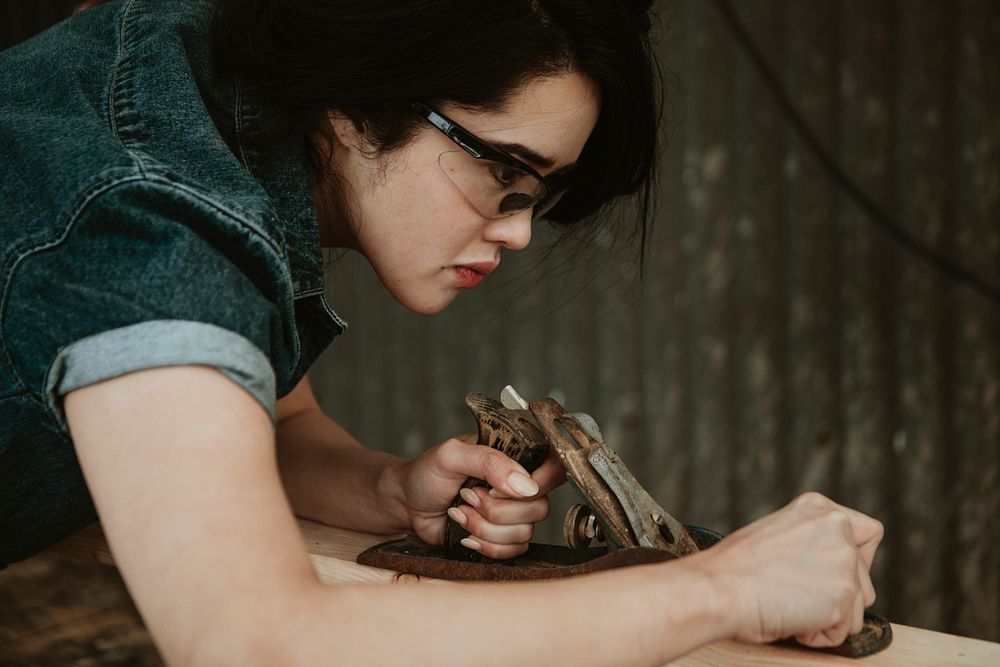 Female carpenter shaping lumber with a hand plane